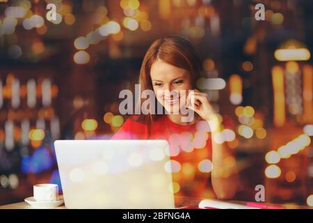 Jeune femme travaillant au bureau et nuit réflexion cityscape sur la fenêtre Banque D'Images