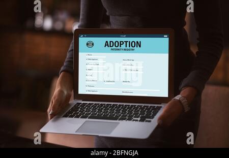 Concept d'adoption. Femme tenant un ordinateur portable. Formulaire de paternité à l'écran Banque D'Images