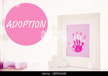 Concept d'adoption. Cadre avec des mains de famille imprime sur la table Banque D'Images
