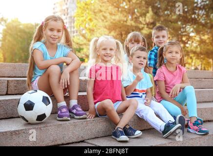 Cute little children with ball assis sur des escaliers à city park Banque D'Images