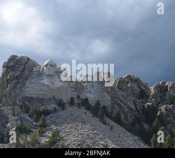 Fin du printemps dans les Black Hills du Dakota du Sud : soleil et ombres sur le monument commémoratif national du Mont Rushmore à l'approche des nuages de tempête Banque D'Images