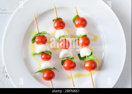 Brochettes de salade Caprese sur plaque blanche : vue du dessus Banque D'Images