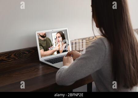 Femme regardant la formation en ligne pour l'artiste professionnel de maquillage sur ordinateur portable à la table Banque D'Images