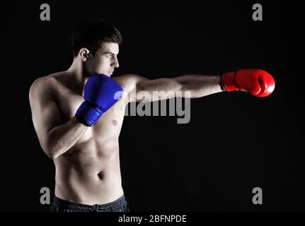 Homme portant des gants de boxe rouge et bleu sur fond noir. Concept de confrontation politique entre les principaux partis américains - démocrates et Republii Banque D'Images
