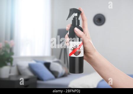 Femme tenant une bouteille de détergent anti-bug dans la chambre Banque D'Images