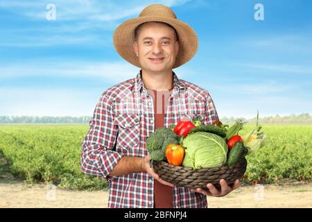 Agronome tenant la vaisselle avec divers légumes dans le champ Banque D'Images