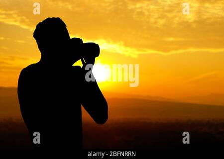 Silhouette d'un photographe professionnel prenant des photos de paysages magnifiques au coucher du soleil Banque D'Images