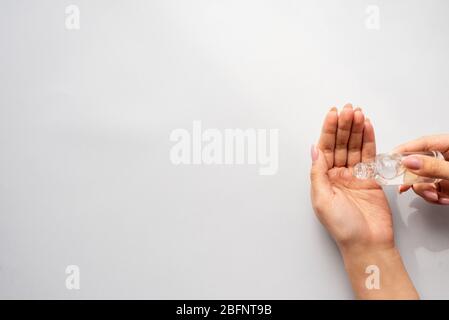 Verser du gel de désinfection sur les mains. Femme à la main utilisant du gel de lavage à l'alcool pour nettoyer le distributeur de pompe à gel aseptisant sur fond bleu, concept de soins de santé. Banque D'Images