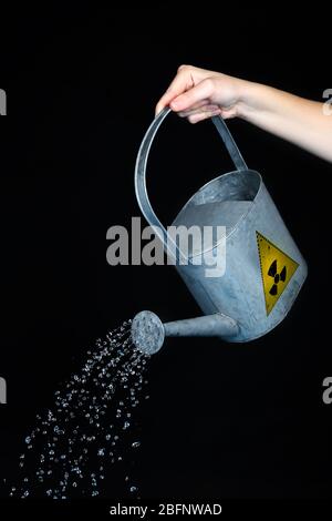 Concept de pollution environnementale. Femme qui verse de l'eau toxique du CAN sur fond noir Banque D'Images