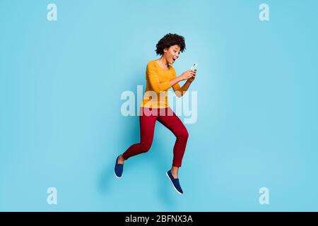 Pleine longueur de la taille du corps de sa belle belle fille positive heureuse gaie gaie gaieté bondée de saut à l'aide de la cellule ayant amusant isolé sur Banque D'Images