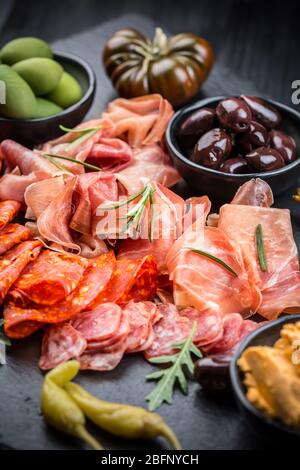 Plateau d'antipastis avec un mélange de salami, prosciutto, chorizo, poivrons, tomates et olives Banque D'Images