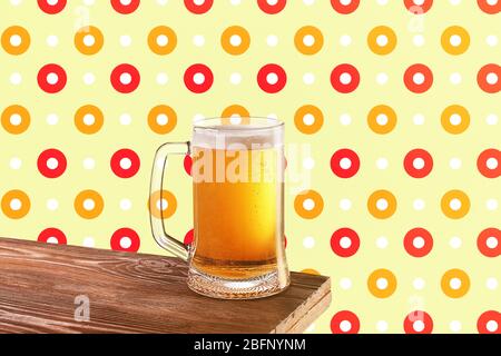 Tasse de bière en verre sur table en bois sur fond à motifs Banque D'Images