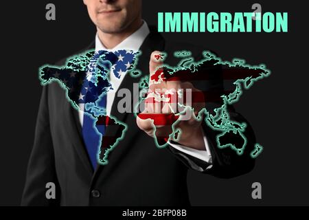 Word IMMIGRATION, homme de pousser le bouton avec le drapeau américain et la carte du monde sur l'écran virtuel contre fond sombre Banque D'Images