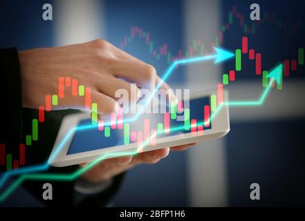 Homme d'affaires travaillant avec des tablettes et des graphiques virtuels, closeup. Concept de négociation financière Banque D'Images