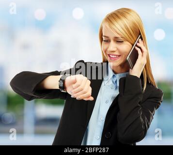 Femme d'affaires regardant la montre de poignet sur fond flou Banque D'Images