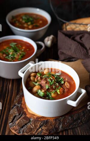 Soupe aux haricots avec viande et légumes servis sur une table rustique et une table en bois avec pain et ail. Soupe traditionnelle des Balkans Pasulj (Grah). Gros plan Banque D'Images