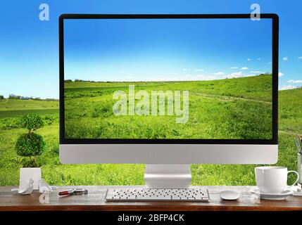 Image conceptuelle d'un espace de travail et d'un bureau d'ordinateur avec herbe verte sur fond bleu ciel Banque D'Images