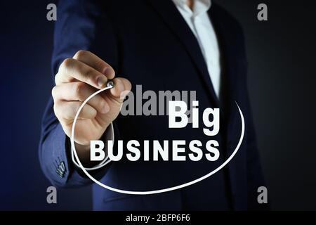 Concept de formation professionnelle. Homme d'affaires en costume avec stylo sur fond sombre Banque D'Images