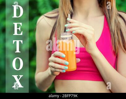 Femme tenant une bouteille avec une délicieuse boisson détox. Texte détox sur fond flou. Detox concept de régime. Banque D'Images