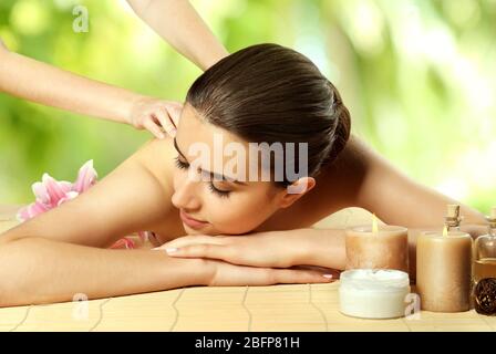 Concept de spa. Belle femme ayant un massage sur table. Arrière-plan avec feuilles de vert flou. Banque D'Images