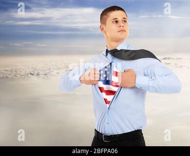 Homme d'affaires montrant le drapeau américain sous le costume sur fond de ciel. Banque D'Images