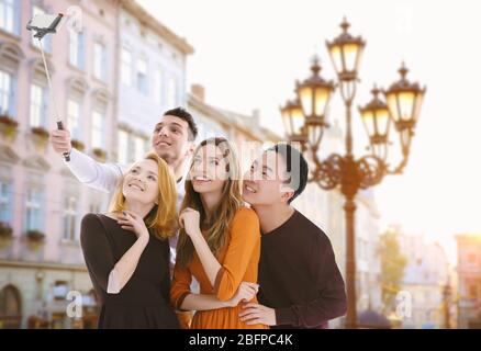 Groupe de jeunes prenant selfie sur fond de rue de ville flou. Banque D'Images