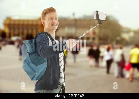 Jeune homme prenant selfie sur fond flou de la place de la ville. Banque D'Images