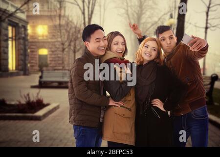 Groupe de jeunes prenant selfie sur fond de rue de ville flou. Banque D'Images