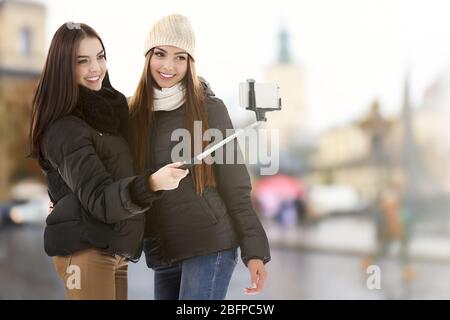 Jeunes femmes heureux prenant selfie sur fond de rue brouillé de ville. Banque D'Images