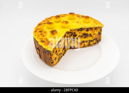 Gâteau de simnel maison traditionnel cuit sur une plaque blanche pour Pâques - gâteau aux fruits recouvert de garniture de massepain jaune grillé et de boules Banque D'Images