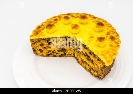 Gâteau de simnel maison traditionnel cuit sur une plaque blanche pour Pâques - gâteau aux fruits recouvert de garniture de massepain jaune grillé et de boules Banque D'Images