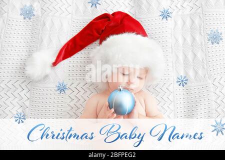 Concept de choisir les noms de bébé de Noël. Petit enfant à Santa Hat avec jouet allongé sur le plaid Banque D'Images