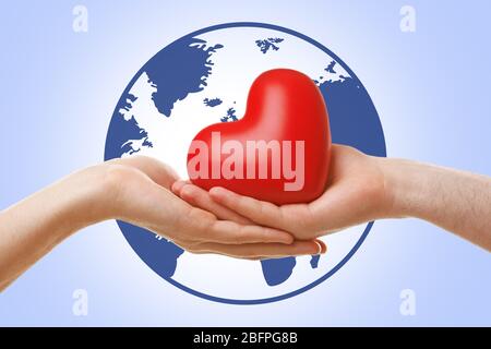 Femme avec homme tenant le coeur dans les mains et globe sur fond. Concept de terre Banque D'Images