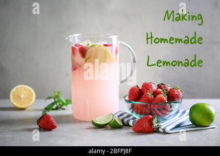 Pichet en verre de boisson rafraîchissante avec citron vert et fraise sur table. Texte FAISANT MAISON DE LA LIMONADE sur fond Banque D'Images