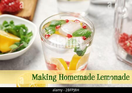 Verre de boisson rafraîchissante avec citron et texte FAISANT MAISON DE LA LIMONADE sur fond clair Banque D'Images