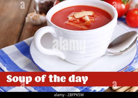 Soupe de tomates savoureuse dans la tasse sur fond de bois Banque D'Images