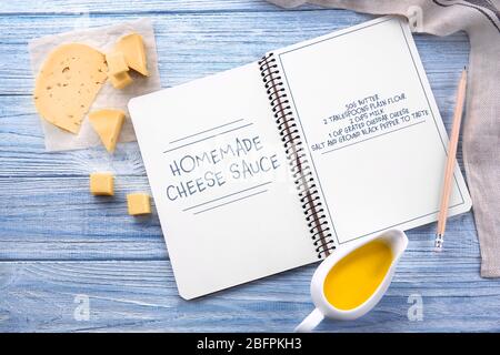 Cahier avec sauce au fromage et ingrédients alimentaires sur fond en bois Banque D'Images