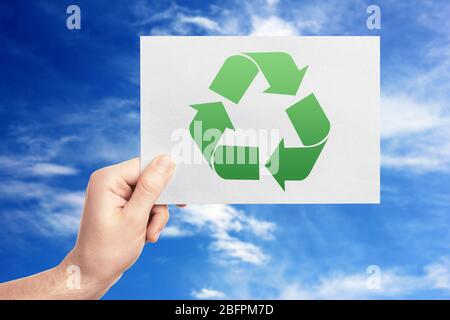 Concept de conservation et de protection de l'environnement. Homme tenant du papier avec symbole de recyclage sur fond de ciel Banque D'Images