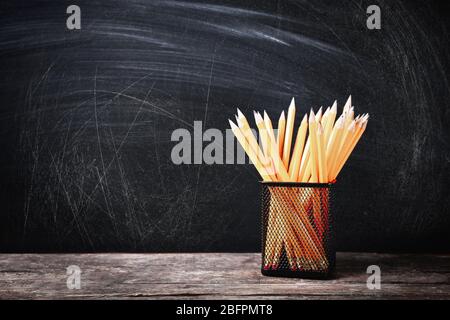 Porte-crayons sur table en bois contre tableau noir de l'école Banque D'Images