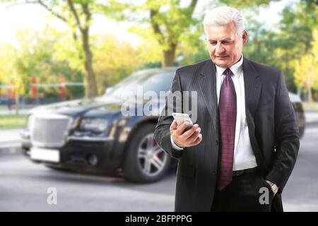 Agent d'assurance utilisant smartphone et voiture en arrière-plan Banque D'Images