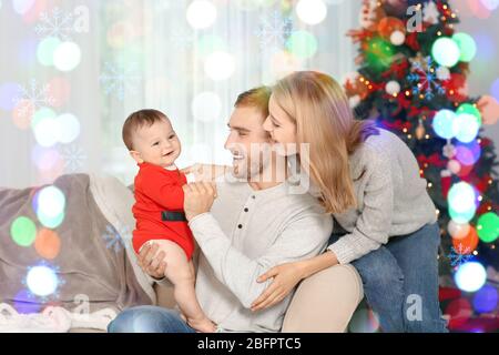 Parents avec bébé en costume de l'aide de Santa à la maison. Concept de célébration de Noël Banque D'Images