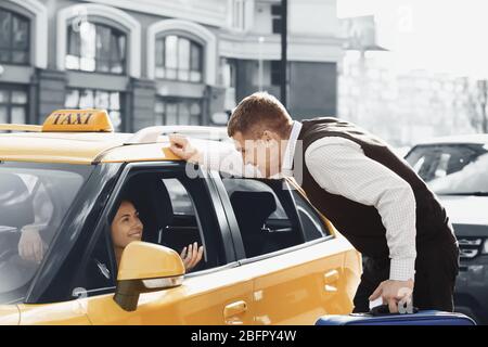 Homme parlant au chauffeur de taxi par la fenêtre ouverte Banque D'Images