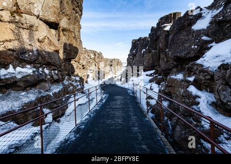 Chemin à travers la ligne de faille Almannagja dans la crête de l'Atlantique milieu dans le parc national de Thingvellir (Þingvellir) dans le sud-ouest de l'Islande dans la neige en hiver Banque D'Images