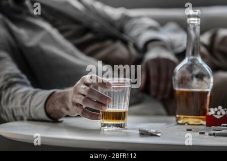 Un homme ivre avec verre et une bouteille d'alcool à la table Banque D'Images
