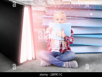 Petite fille mignon lecture conte de fées près de livres géants sur table Banque D'Images