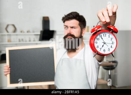 Appelez pour la livraison. Heure du repas. Nourriture et boissons saines. Femme de ménage dans la cuisine. Cuisine par recette. Menu hippster barbu. Foyer sélectif. Espace de copie. Homme avec planche et réveil. Banque D'Images