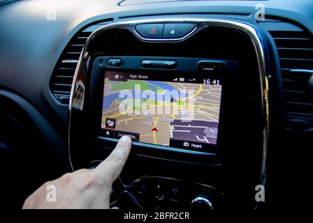Gros plan sur un doigt qui commande une unité de navigation satellite ou gps à l'intérieur d'une voiture Banque D'Images