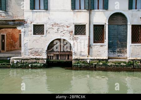 Une porte de canal à une résidence avec une entrée de garage en bateau. Des marches vont du canal à une allée près de la maison. Venise Italie. Pas de gens Banque D'Images