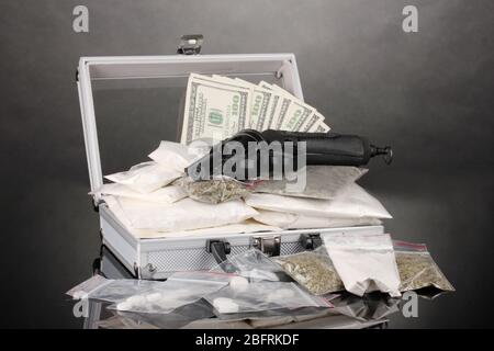 Cocaïne et marijuana avec un pistolet dans une valise sur fond gris Banque D'Images