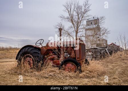 Coderre, SK- 9 avril 2020 : un tracteur McCormick Deering vintage avec l'ascenseur de Coderre, Saskatchewan en arrière-plan Banque D'Images